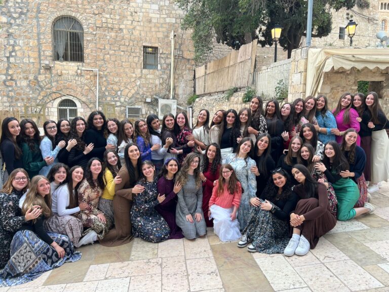 Group of women posing outdoors by stone wall